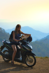 Naklejka na ściany i meble Tourist in Thailand on a Motorcycle Girl looking at the map