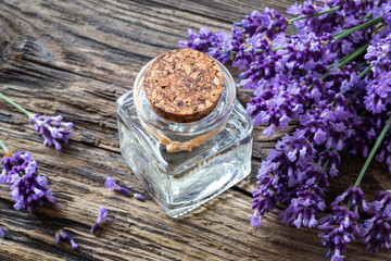 Obraz na płótnie Canvas A bottle of lavender essential oil with lavender flowers