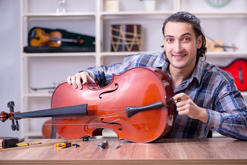 Young handsome repairman repairing cello © Elnur