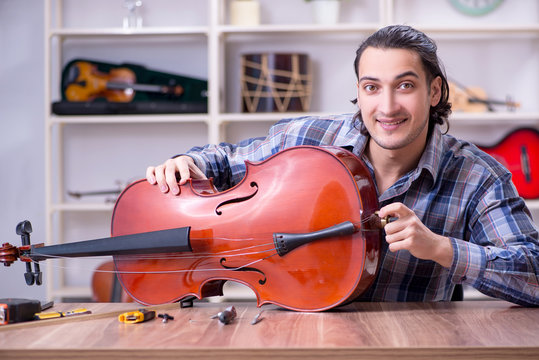Young handsome repairman repairing cello