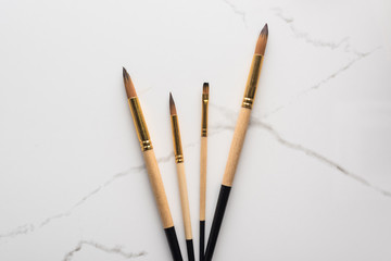 top view of paintbrushes on marble white surface with copy space