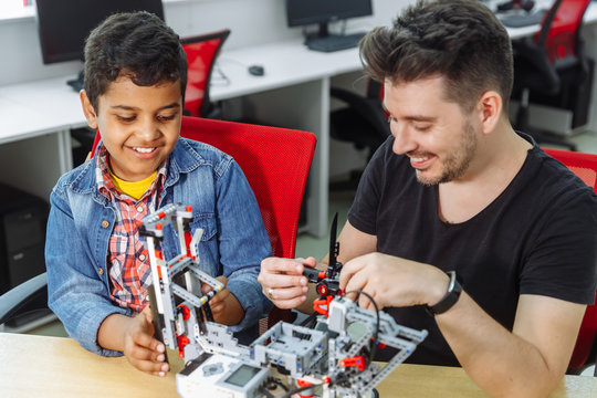 Mixed Racial group of School children controlling robotic machine with remote control together teacher. Creative kids working on the tech project at school.