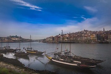 Fototapeta premium Traditional boats with barrels on the Douro river, Ribeira and Dom Luis bridge, Porto, Portugal.