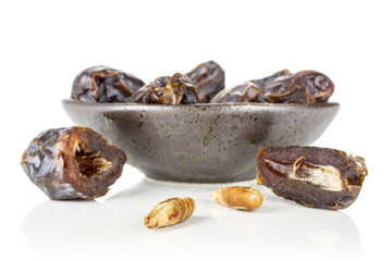 Group of lot of whole two halves of dried brown date medjool on grey ceramic plate isolated on white background
