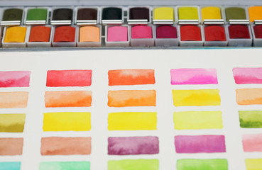 Box with watercolors and palette on a light copy space gray background.