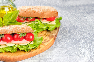 Sandwich with cheese, cucumber and Cherry Tomato on a wooden board. The sandwich is decorated with a lettuce leaf and cherry tomatoes.