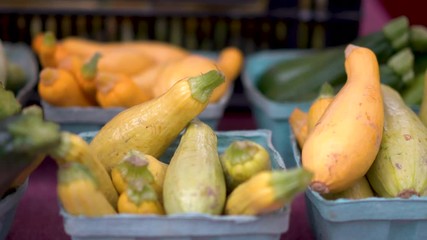 Slide to the left showing different types of squash at an outdoor farmers market.