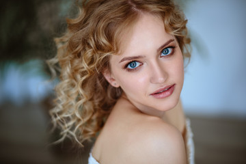 Close up portrait of blonde charming young woman with curly hair and natural makeup. Sunny morning, spa and care