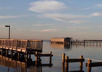 Fototapeta premium A storm damaged pier and boathouse on a river at sunset