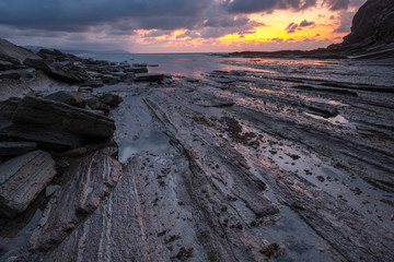 Sunset with its impacted rock formations on Itzurun beach (Zumaia, Basque country, Spain)