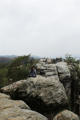 Young hiker girl on top of the rocks views into the distance.
