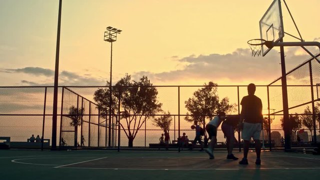 Sunset Basketball Game captures a group of young men playing basketball at sunset, creating a silhouette look.                                                                                          