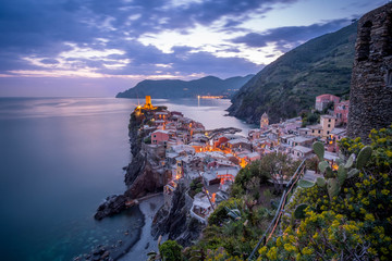 Vernazza Night view from hill of houses with lit light and blue sea, one of Cinque Terre villages , Liguria, Italy