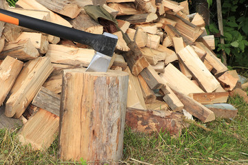Chopped firewood and an ax stuck in a tree stump. Preparing firewood for the winter in the village, environmentally friendly fuel. Concept of preserving the environment