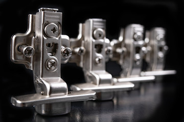 Metal furniture hinges with hydraulic brake. Furniture accessories for the production of furniture on a dark table.