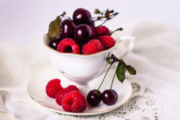 Cup with saucer and berries on white background