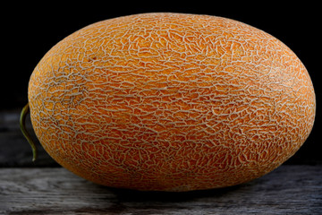 Whole fruit of a melon with a knife on an old rustic table.