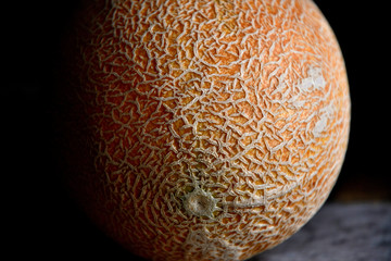 Whole fruit of a melon with a knife on an old rustic table.