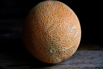 Whole fruit of a melon with a knife on an old rustic table.