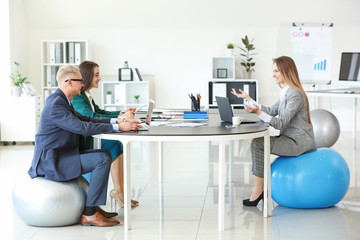 Young business people sitting on fitballs while working in office © Pixel-Shot