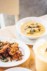 Thai style homemade deep fried chicken wings on white plate so delicious and crispy. And green curry on background. Street food.