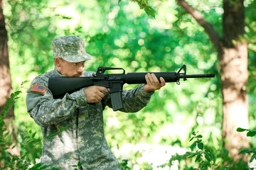 Soldier in camouflage taking aim in forest
