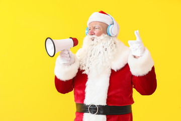Portrait of Santa Claus with megaphone listening to music on color background