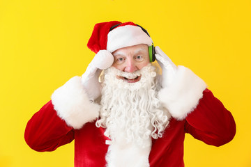 Portrait of Santa Claus listening to music on color background