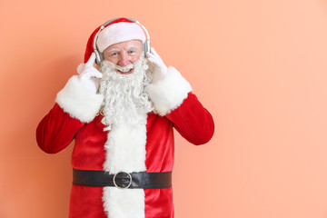 Portrait of Santa Claus listening to music on color background