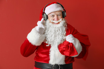 Portrait of Santa Claus listening to music on color background