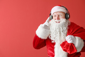 Portrait of Santa Claus listening to music on color background