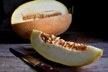 Sliced melon and knife on a wooden table.