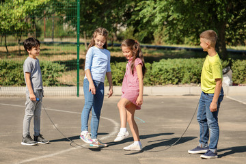 Cute little children jumping rope on playground