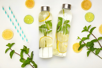 Bottles of fresh infused water and ingredients on white background