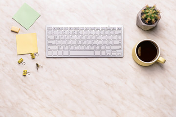 Modern computer keyboard with stationery and cup of coffee on light  background