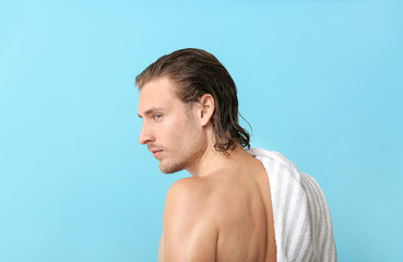 Naklejka premium Handsome young man after washing hair against color background