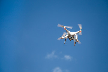 white drone hovering in a bright blue sky. New technology in the aero photo shooting.UAV drone...