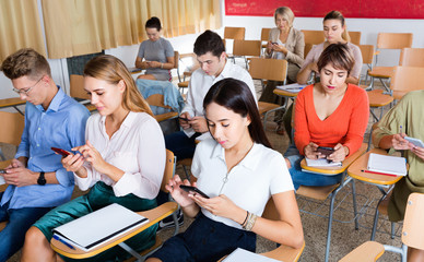 Students using smartphones to find necessary information on lecture in university class