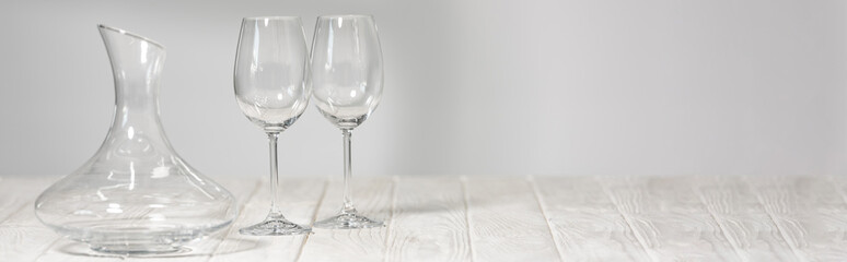 panoramic shot of empty wine glasses and jug on wooden surface