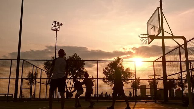 Sunset Basketball Game This stock footage captures a group of young men playing basketball at sunset, creating a silhouette look.