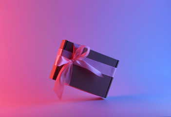 Gift box with pink ribbon in neon light