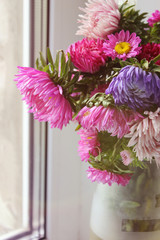 bouquet of asters in a vase on a wooden background