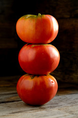 Ripe red tomatoes stacked in an orderly manner on an old rustic table.