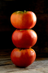 Ripe red tomatoes stacked in an orderly manner on an old rustic table.