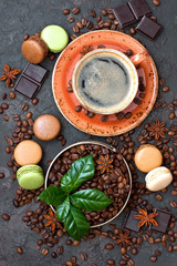 Coffee cup, beans, macaroons and chocolate on  table