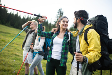 Group of hikers with backpacks and sticks walking on mountain. Friends making an excursion