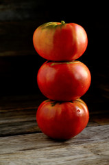 Ripe red tomatoes stacked in an orderly manner on an old rustic table.