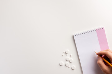 Obraz premium Mаle hand, notepad, pencil, drugs on white background. Flat lay.