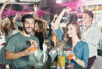 adult male with smiling female are talking and drinking cocktail