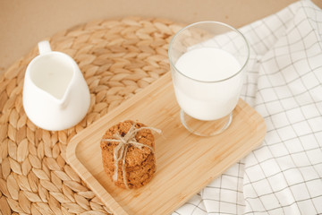 oatmeal cookies and a glass of milk are on a wicker napkin on the table